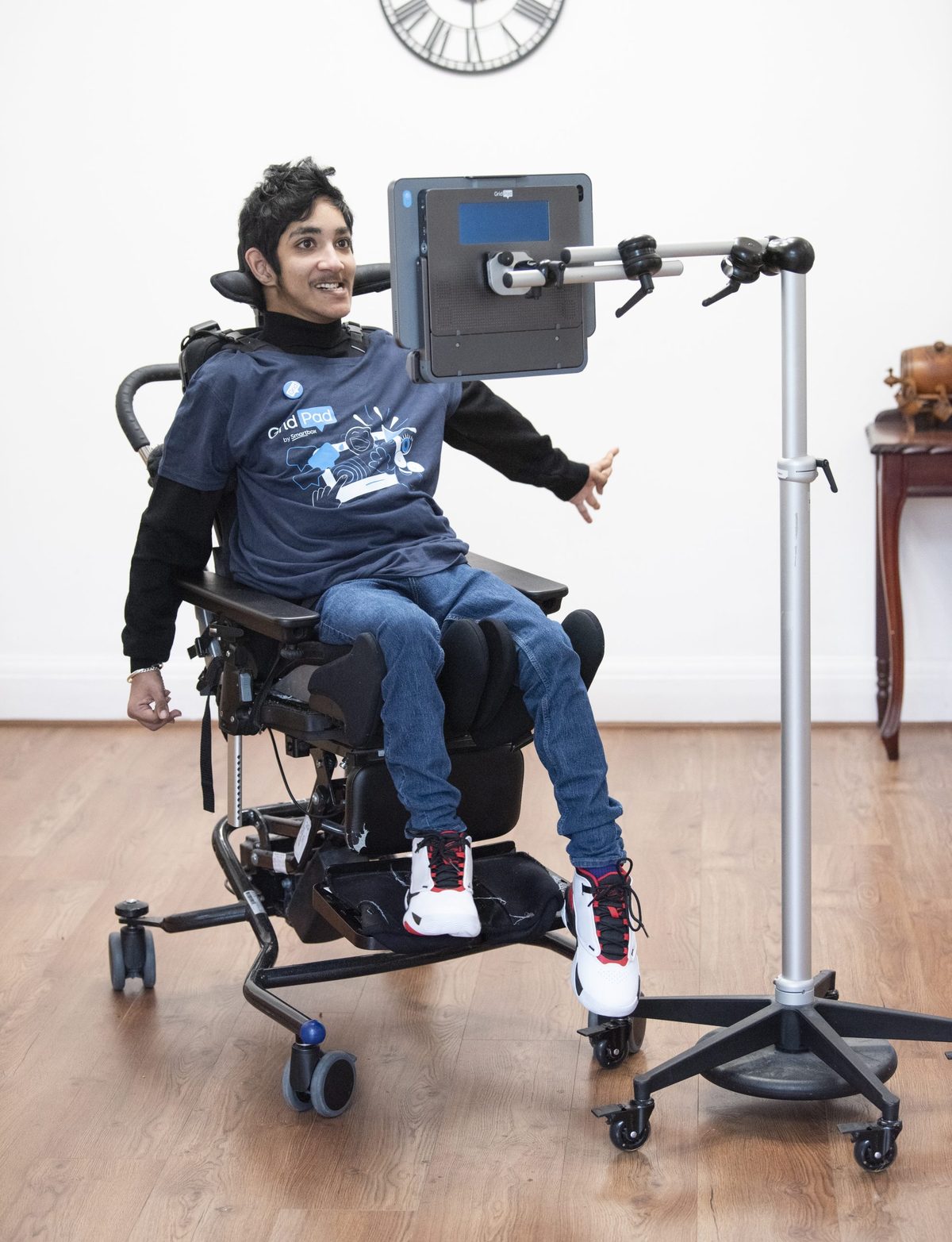 Ein junger Mann im Rollstuhl vor einem Sprachcomputer mit Augensteuerung auf einem Rollständer